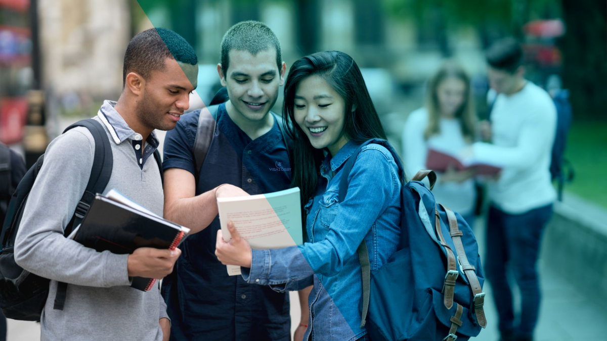 Three international students are looking at the book and smiling.