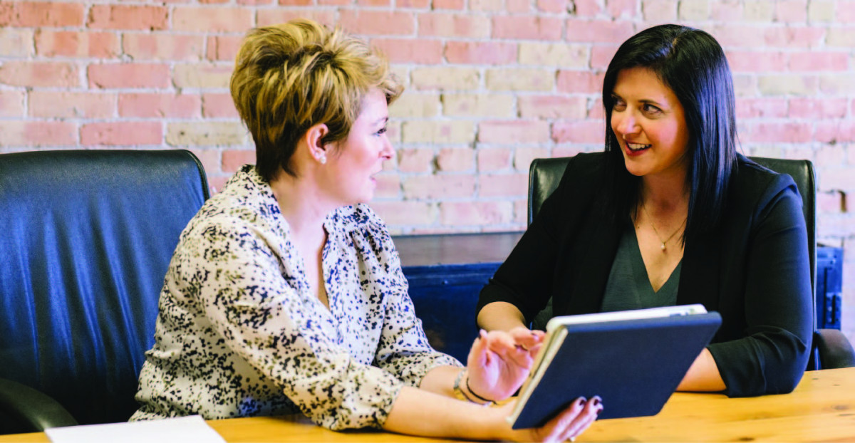 Two women sitting on chairs & talking - Benefits of Hiring Visa and Immigration Consultants