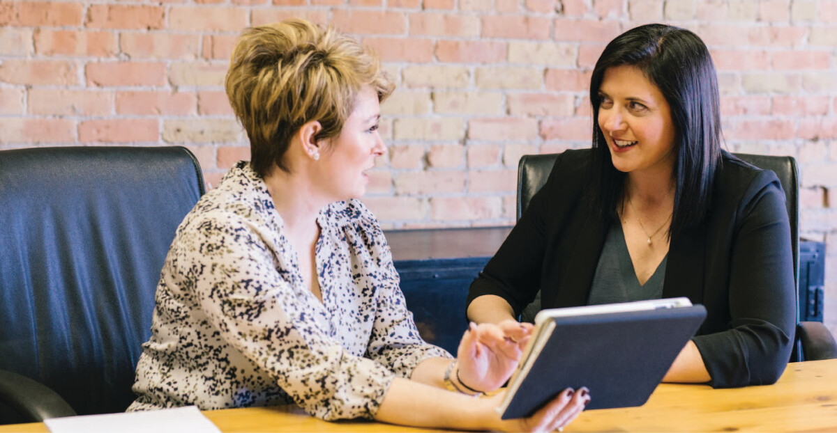 Two women sitting on chairs & talking - Benefits of Hiring Visa and Immigration Consultants