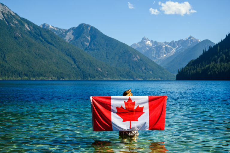 A man holding Canadian flag on his back - Canada Is Inviting 431,645 Permanent Residents