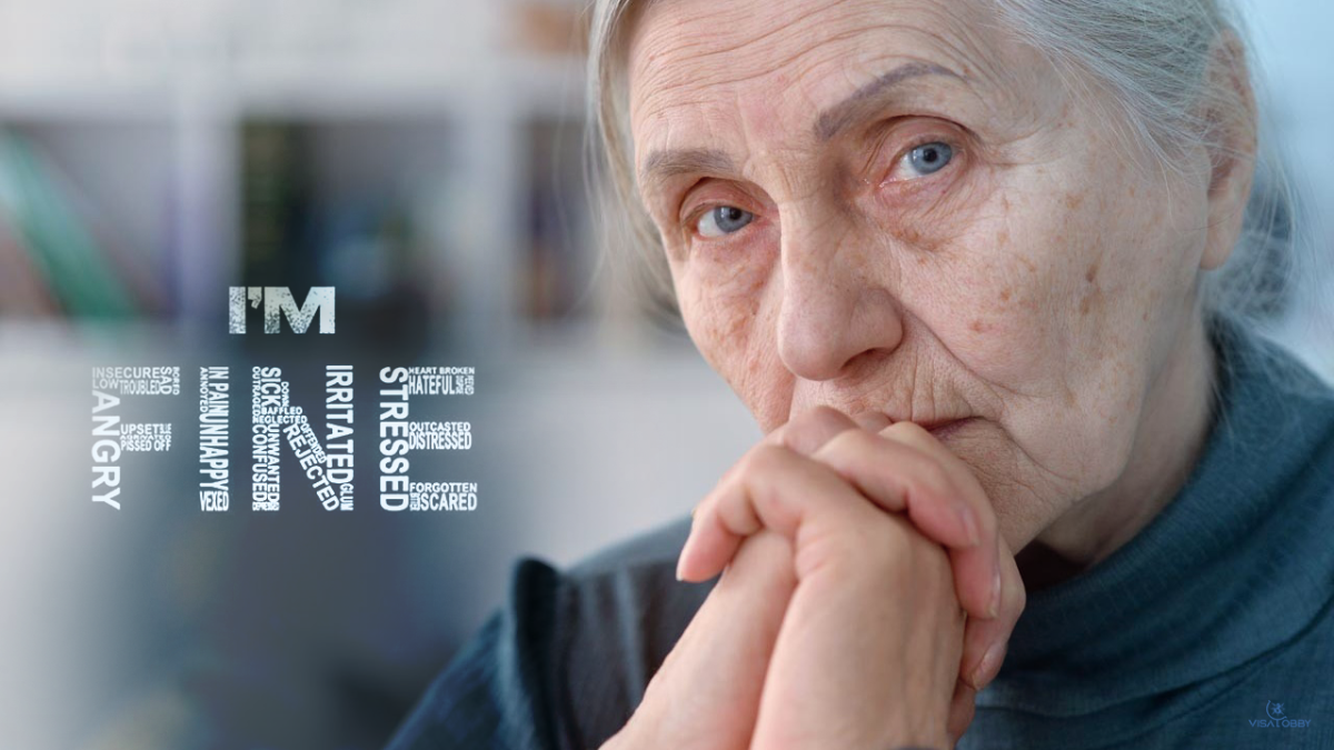 An elderly woman sitting with folded hands near to her face and thinking