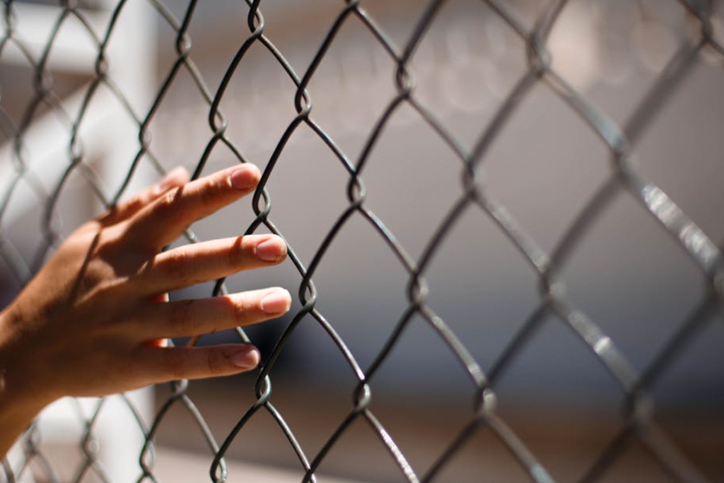 A hand touching the bars - Australia's Indefinite Detention Laws