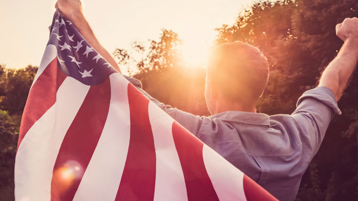 A person holding a US flag - New Act to Eliminate Green Card Country Quota