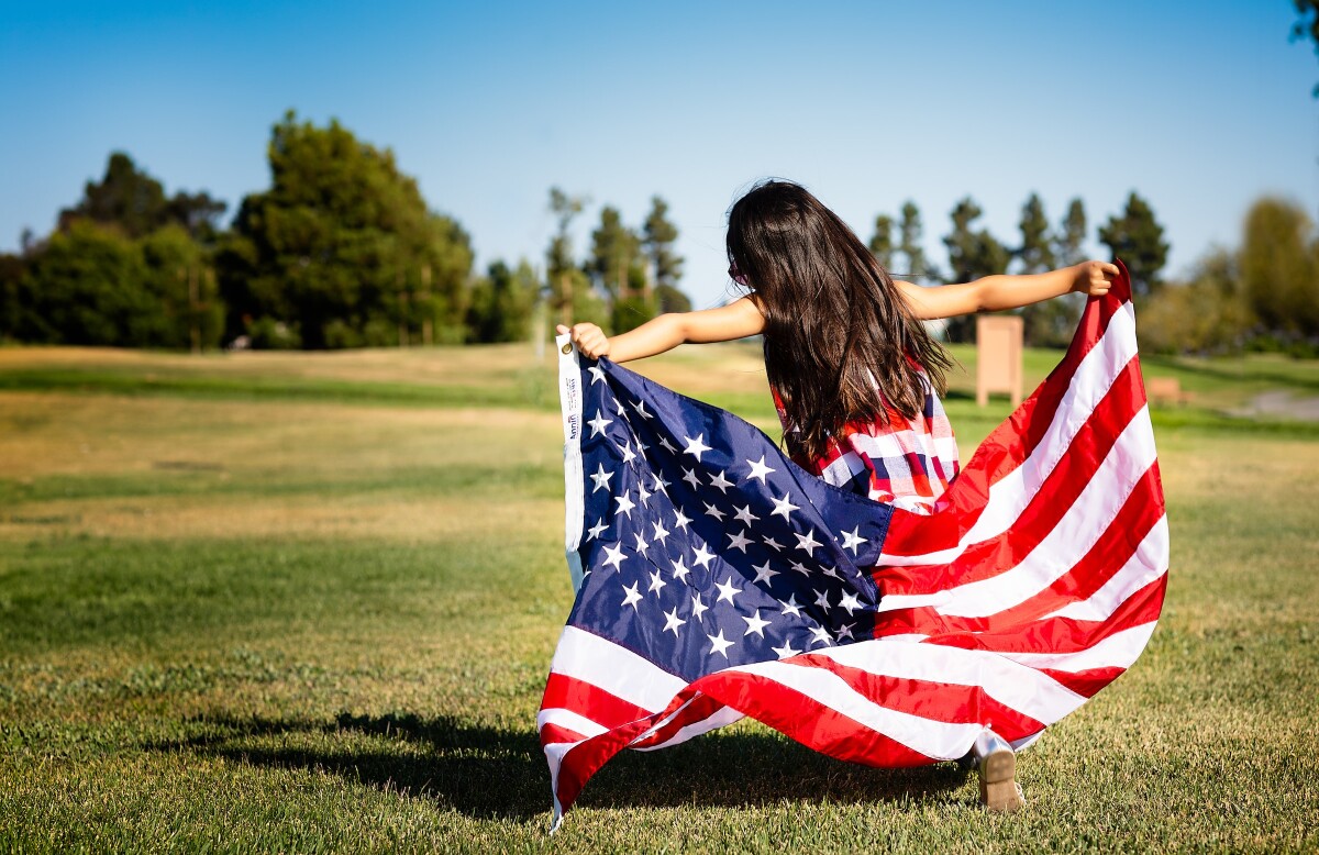 A little girl holding USA flag - The US Green Card