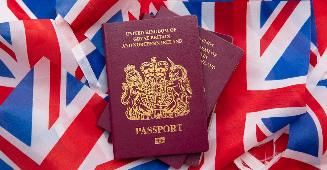 British passport with flags in the background - Immigrants losing British Citizenship after naturalization