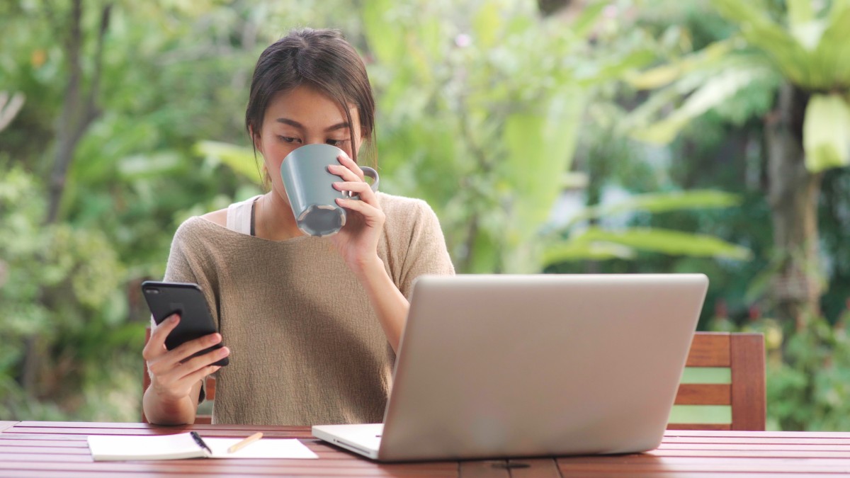 A digital nomad enjoying coffee while working on laptop - Digital Nomad Visa Spain